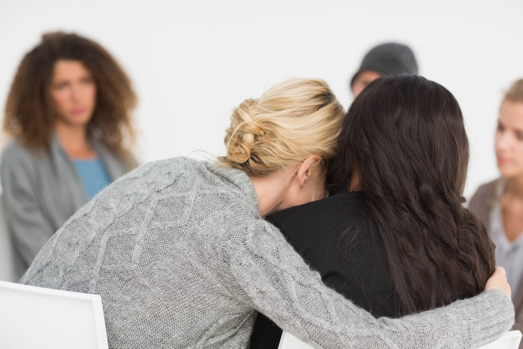 Two women hugging at a group therapy session