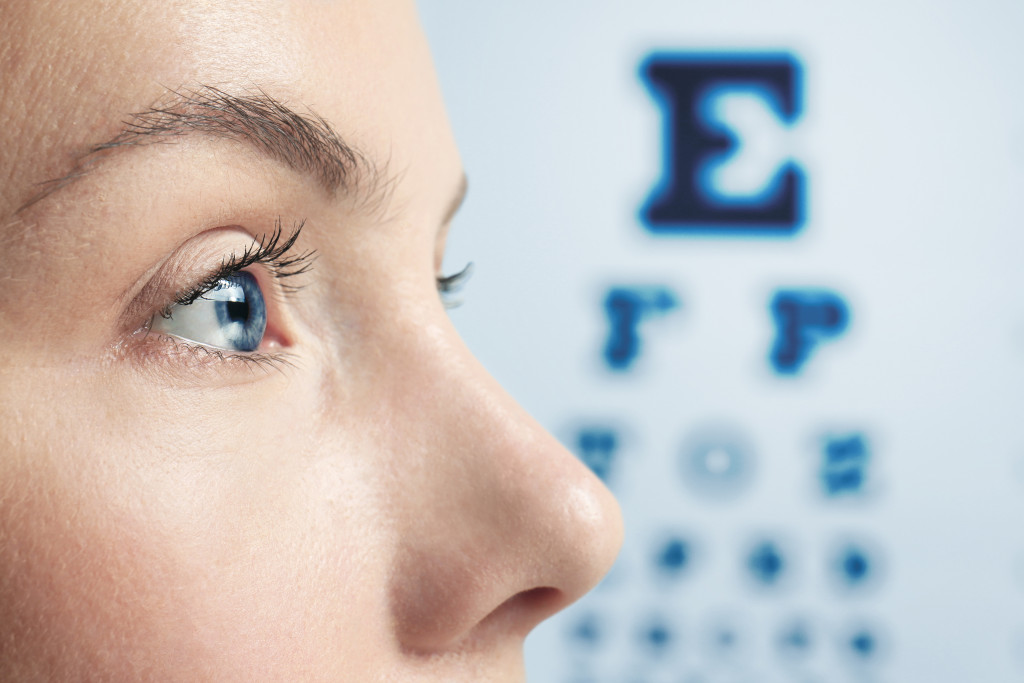 woman with blue eyes looking ahead with eye exam chart on the background