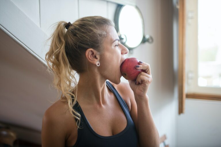 A Woman in Tank Top Eating an Apple