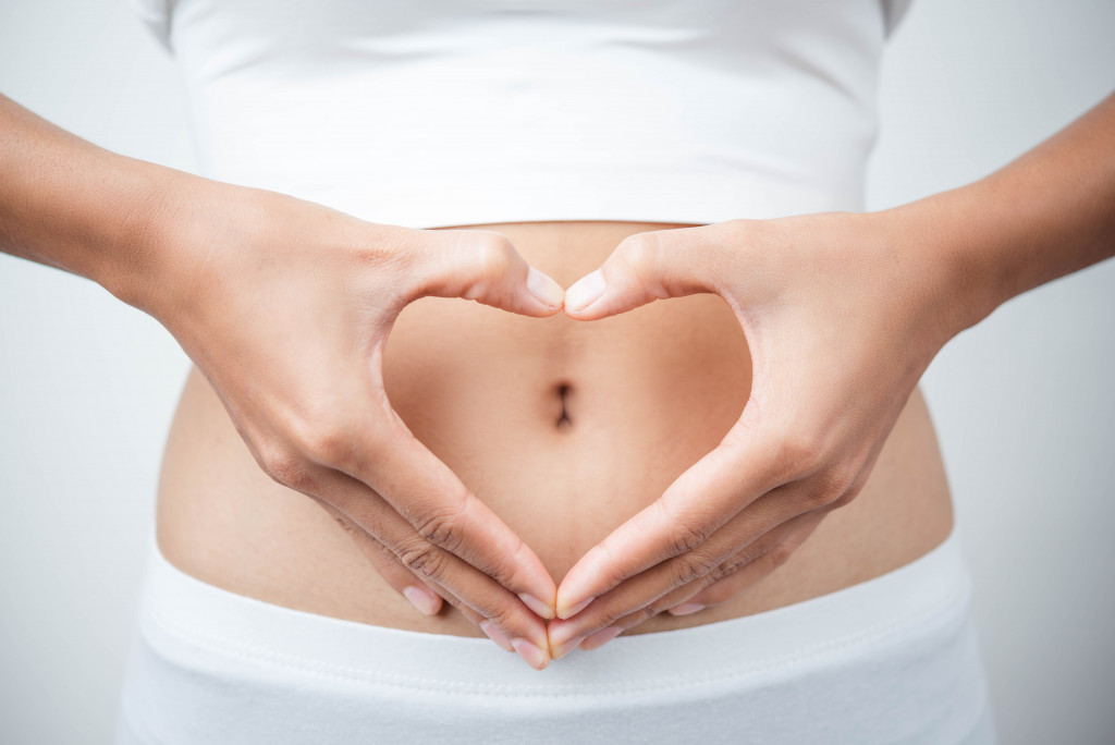 woman doing hand heart shape in her belly