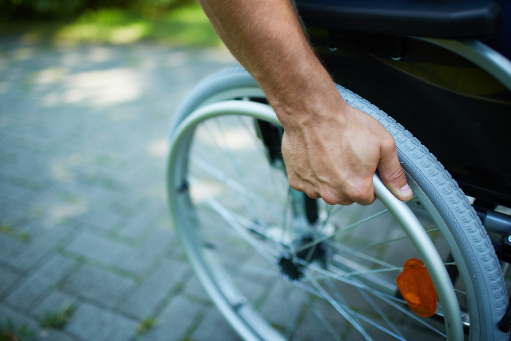 A disabled person's hand on the wheel of his wheelchair